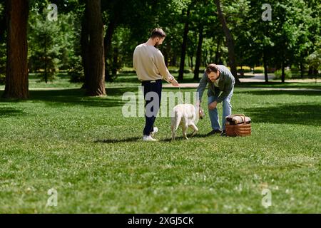 A gay couple with beards enjoys a sunny afternoon in a park with their labrador dog. Stock Photo