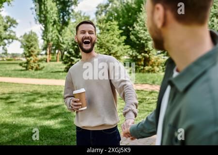 A bearded gay couple enjoys a sunny afternoon in the park, holding hands and laughing. Stock Photo