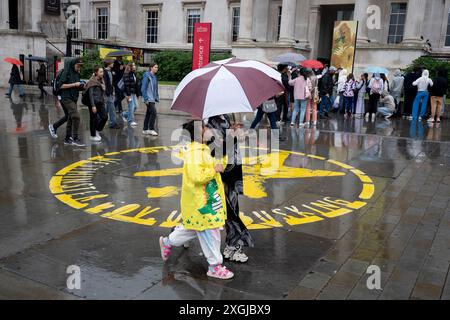 Visitors to the capital pass the National Gallery in Trafalgar Square during yet another rainy day in the capital, on 9th July 2024, in London, England. Many parts of the UK have already had their average monthly rainfall  with 66cm of rain on the first seven days of the month - 139% of the total expected for the whole of July. (Photo by Richard Baker / In Pictures via Getty Images) Stock Photo