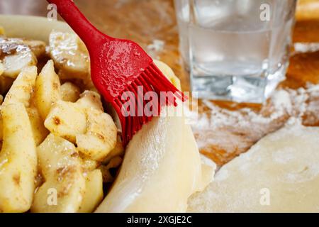 Making a pie:  Top crust.  Edges of apple pie are basted with water. Stock Photo