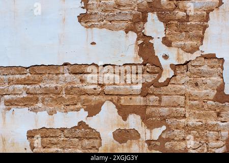 Old wall showing layers of peeling paint, exposing the aged brick surface. Stock Photo