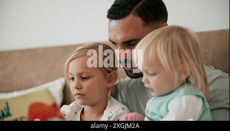 Father, children and reading book in bed for storytelling, literature and bonding at bedtime. Home, daddy and daughters learning together for love Stock Photo