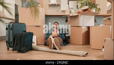 Man, boxes and sleeping on floor in new house with fatigue from travel, immigration and real estate investment. Person, tired and rest for relief Stock Photo