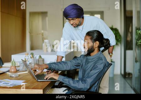 Young office working showing financial report detail on laptops screen while boss studying it very carefully Stock Photo