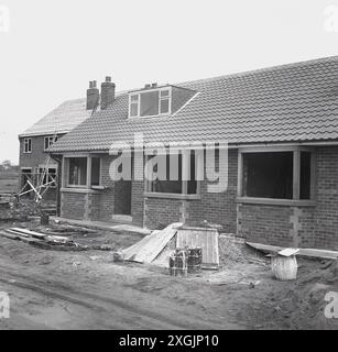 1970s, historical, new homes being built, a chalet bungalow under construction, brick-built, single storey, with bedroom in loft,, England, UK. Also called a dormer bungalow, this type of home is a one and half storey house, with an upper room within the pitched roof. Stock Photo