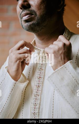 Medium close up of middle aged Indian man adjusting flax collar Stock Photo