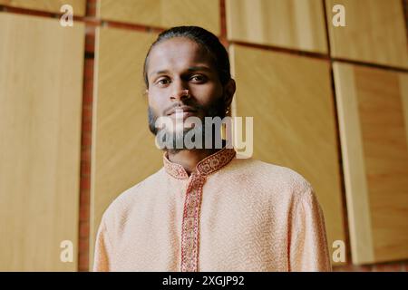 Low angle shot of young Indian model with silver nose piercing and dressed in traditional Indian costume smirking while looking at camera Stock Photo