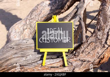 Ideal customer symbol. Concept words Ideal customer on beautiful black yellow blackboard. Beautiful tree background. Business ideal customer concept. Stock Photo