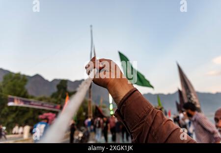 A Kashmiri Shia Muslim man pulls the rope of a tall religious flag ...