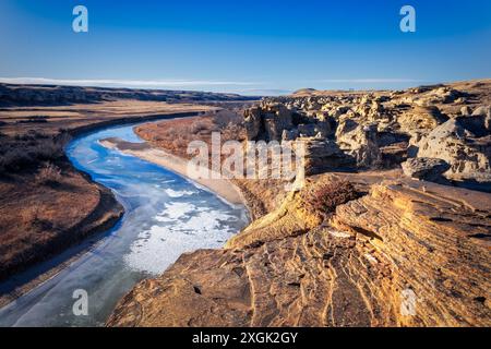 Scenic landscape featuring a partially frozen river flowing through a canyon with rock formations Stock Photo