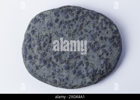 Round, flat, grey sea or river stone textured by erosion. Stock Photo