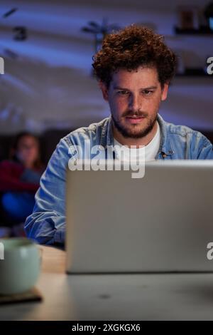 Caucasian man using laptop at home working late at night concentrated. Stock Photo