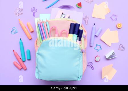 Composition with stylish school backpack and different stationery on lilac background Stock Photo