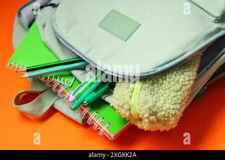Backpack with school supplies on orange background Stock Photo