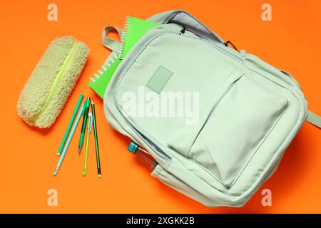 Backpack with school supplies on orange background. Top view Stock Photo