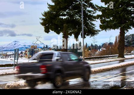 A passing car in the foreground. Scenic view of a residential area with traditional buildings against the sky and mountains in the background. Stock Photo