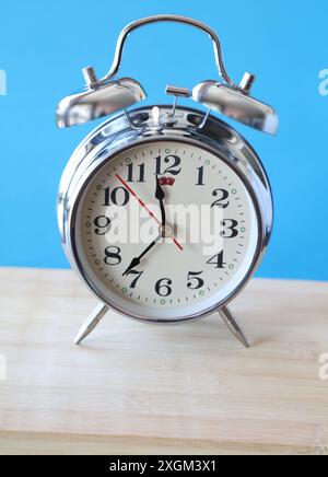 Retro alarm clock on table in front of blue background Stock Photo