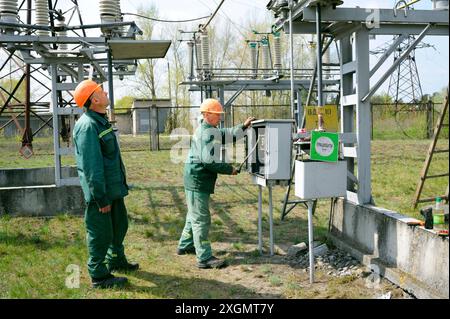 Power substation. Worker checking connections on the electric board, engineer watching. May 5, 2018. Oseschina, Ukraine Stock Photo