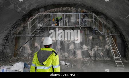 Inside view of a tunnel construction site with workers in safety gear working on scaffolding Stock Photo