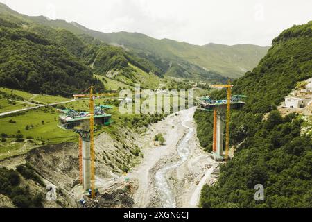 Kazbegi, Georgia - 7th july, 2024: aerial view cranes and bridge foundation pillars on construction site of new highway road project built by chinese Stock Photo