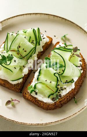 Breakfast, cereal bread sandwiches, cream cheese, sliced cucumber, with micro greenery on a light table, close-up, top view, selective focus, no Stock Photo