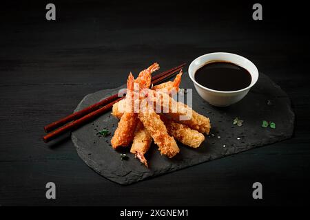Shrimp in tempura, deep-fried, on black slate, with soy sauce, horizontal, no people Stock Photo