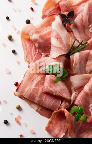 Raw bacon, sliced, with micro greenery and spices, on a white background, close-up Stock Photo