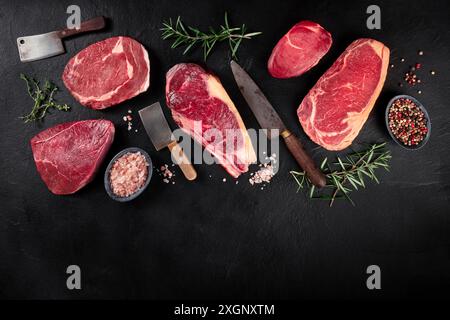 Meat banner with copy space. Different beef steaks, shot from the top on a black background, with knives and spices Stock Photo