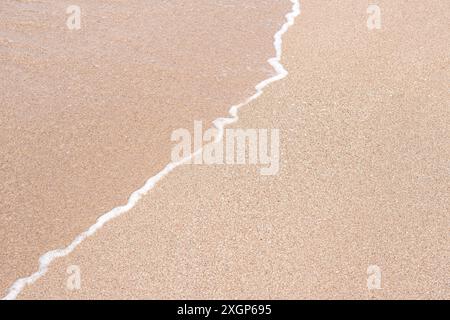 Soft beautiful sea wave on sandy beach. Background texture. Wet Sandy beach Stock Photo