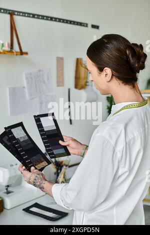 A young man meticulously examines fabric swatches in his clothing restoration atelier, showcasing his dedication to sustainable fashion. Stock Photo