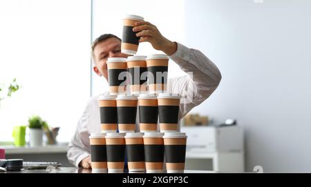 Stupid office clerk making huge tower out of paper cups close-up Stock Photo