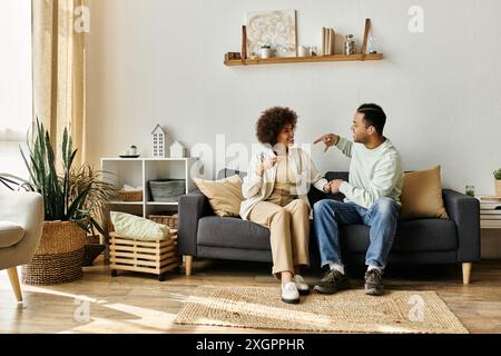 An African American couple sits on a couch at home and communicates using sign language. Stock Photo