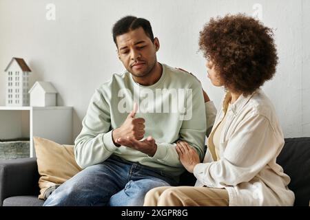 An African American couple communicates using sign language while sitting on a couch at home. Stock Photo