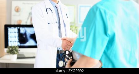 Two doctors in office shaking hands celebrating successful treatment Stock Photo
