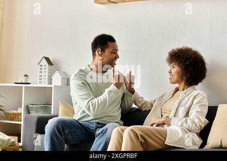 An African American couple communicates using sign language while relaxing on their couch at home. Stock Photo