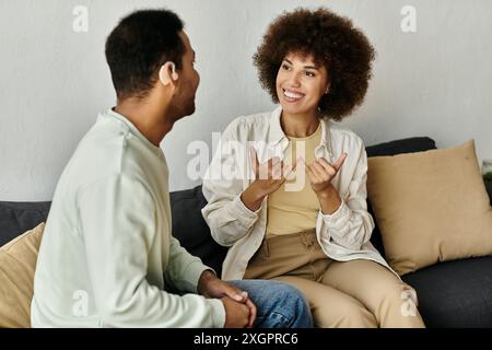 An African American couple communicates using sign language while sitting on a couch. Stock Photo