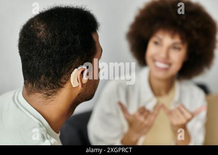 A young African American couple sits at home, communicating in sign language. Stock Photo