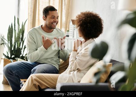 A couple communicates using sign language while sitting on a couch at home. Stock Photo