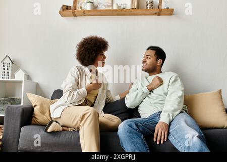 A couple sits on a couch and converses using sign language. Stock Photo