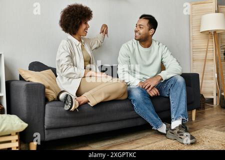 An African American couple sits on a couch in their home, using sign language to communicate. Stock Photo