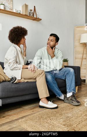 A loving African American couple sits on a couch, using sign language to communicate with each other. Stock Photo