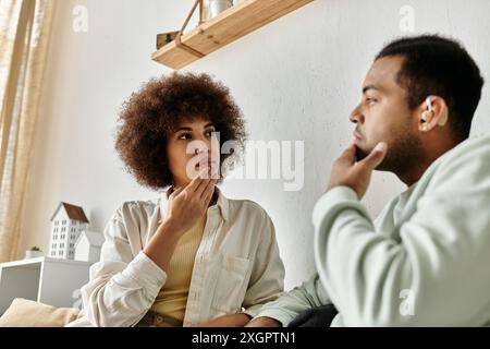 A couple sits at home, using sign language to communicate with each other. Stock Photo