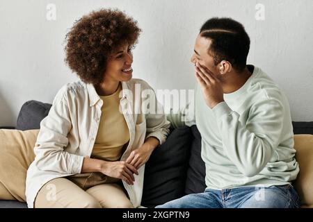 An African American couple sits on a couch and communicates using sign language. Stock Photo