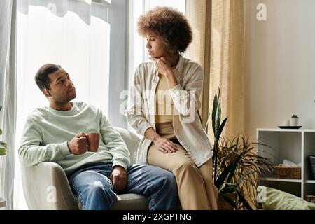 A couple sits in their living room, using sign language to communicate. Stock Photo