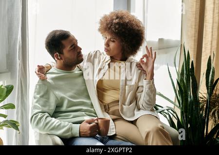 An African American couple sits together, using sign language to communicate at home. Stock Photo