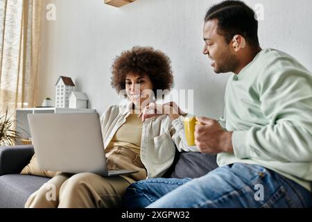 An attractive African American couple communicates using sign language while sitting on a couch. Stock Photo