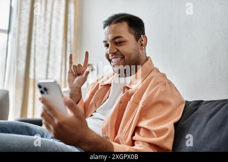 A man smiles as he signs while using his smartphone. Stock Photo