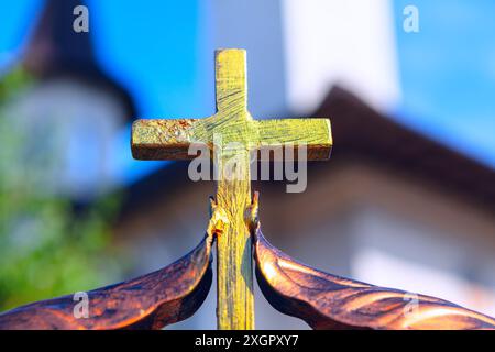 Golden cross is on a metal fence.  Religious symbol on tall metal structure Stock Photo