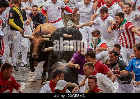 Pamplona, Spain. 10th July, 2024. Several young men run in front of the bulls during the running of the bulls at the San Fermín 2024 festivities. The Fuente Ymbro cattle ranch has starred in the fourth running of the bulls of San Fermín 2024 in Pamplona. It was an immaculate and fast race. Credit: SOPA Images Limited/Alamy Live News Stock Photo