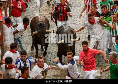 Pamplona, Spain. 10th July, 2024. Several young men run in front of the bulls during the running of the bulls at the San Fermín 2024 festivities. The Fuente Ymbro cattle ranch has starred in the fourth running of the bulls of San Fermín 2024 in Pamplona. It was an immaculate and fast race. Credit: SOPA Images Limited/Alamy Live News Stock Photo